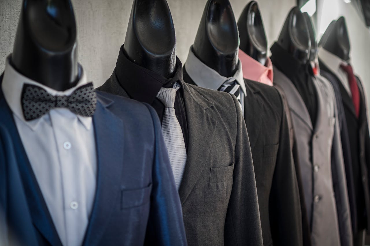 Close-up of mannequins adorned in elegant men's suits in a store setting, showcasing diverse styles.