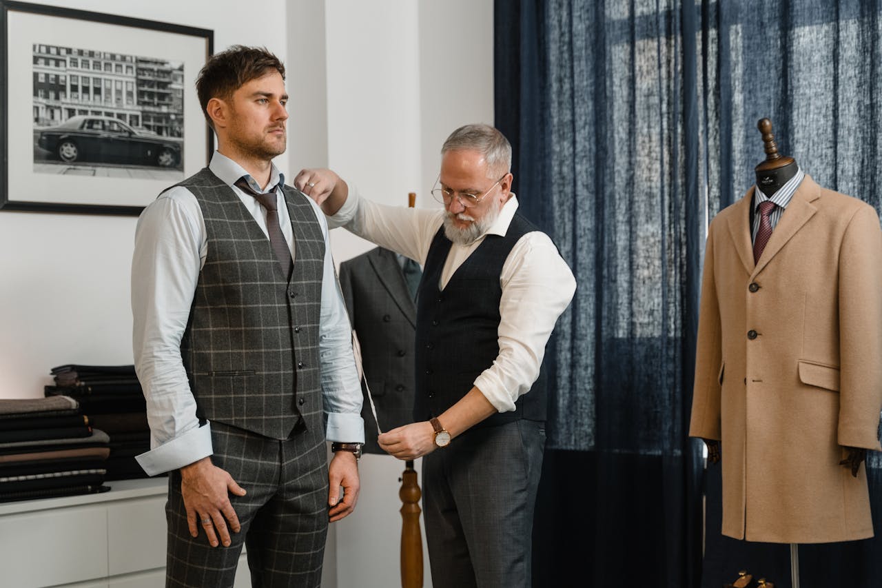 Tailor adjusts a client's suit in a classic atelier setting, emphasizing craftsmanship.
